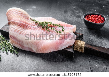 Raw fillet of white fish catfish on a cutting board. Black background. Top view Royalty-Free Stock Photo #1815928172