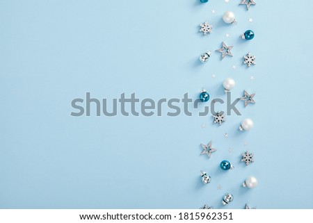 Christmas minimal mockup - white, glass and blue balls, snowflakes and stars confetti on blue background. Horizontal composition, flat lay, top view. Light blue background. Winter backdrop.