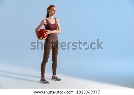 Photo of athletic redhead sportsgirl working out with medicine ball isolated over blue background