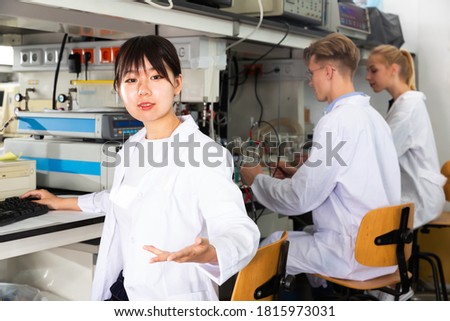 Casual Chinese female scientist near laboratory equipment at biochemical lab