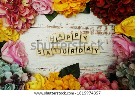Happy Saturday alphabet letter with colorful flowers border frame on wooden background