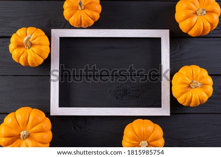 Halloween background. Orange pumpkins and photo frame against  black wood background. Copy space.