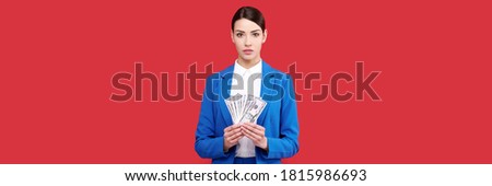 Girl holding money, business woman with stack of dollars, female in blue suit in red isolated background