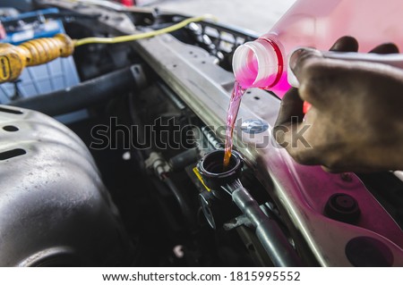 Auto mechanic filling super long life coolant pre-mixed fluid into the car radiator fill hole. Royalty-Free Stock Photo #1815995552