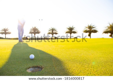 Golf club and ball in grass at the Golf course. White Golf ball on Green field golf course in morning time with sun light. Professional  player fell Excited putting 