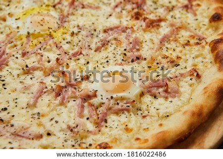 Delicious Italian Pizza Carbonara with Bacon, eggs and mozzarella cheese on dark background