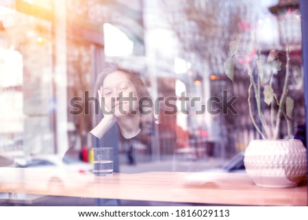 the picture was taken through the window. breakfast - girl sitting with  cup of coffee at the cafe
