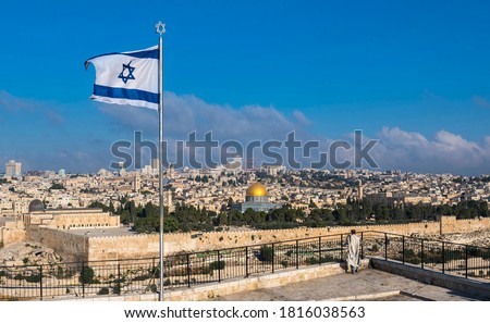 Orthodox Jewish man in tallit prayer shawl and Israeli flag with a Star of David flying over the view of Jerusalem; with Dome of the Rock and the Temple Mount, the Old City wall and the Golden Gate