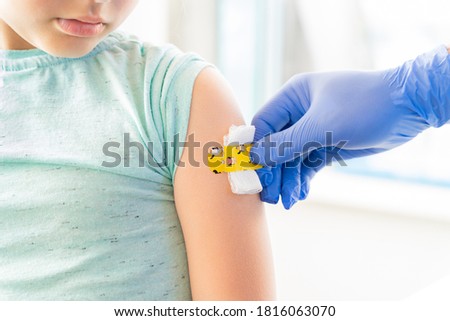 Vaccination of little girl in doctor's office.Kids funny adhesive plaster,gauze napkin.Hand in glove.Vaccine for covid-19 coronavirus,flu,infectious diseases.Injection.Clinical trials for human,child. Royalty-Free Stock Photo #1816063070