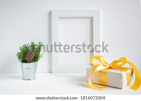 New Year's gift in a box, a bouquet of green fir branches in an iron bucket and a white frame for text on a white background. Christmas composition.