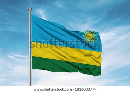Rwanda national flag cloth fabric waving on beautiful sky.