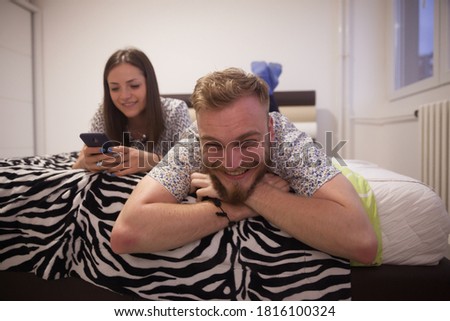 Young couple or brother and sister lying on bed, enjoying their free time.
