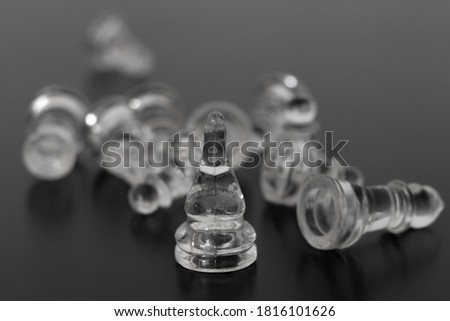 Glass chess pieces scattered on a black background, pieces from a game or organization