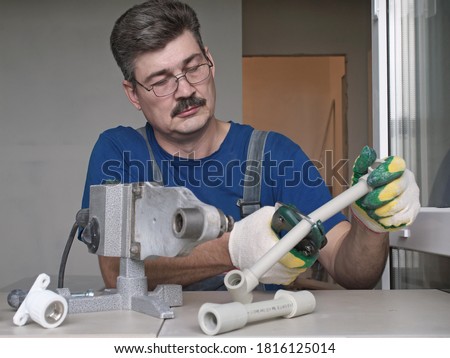 Work on the installation of heating or plumbing.  Male  plumber welding plastic pipes plumbing installation Royalty-Free Stock Photo #1816125014