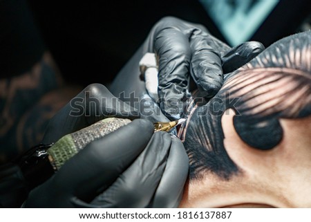 Tattooist doing black tattoo of snake for woman