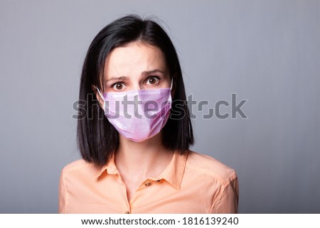 woman in shirt and medical mask, gray background