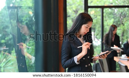 Portrait of business woman while  hand holding stylus pen and tablet for planning working in meeting room.