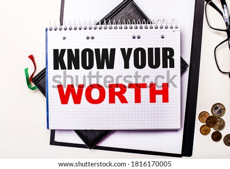 KNOW YOUR WORTH is written on white paper next to diaries, glasses and coins.