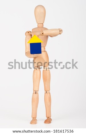 Small wood mannequin sit holding colourful block house isolated on white background