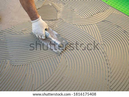 
The worker applies the glue to a tile on a concrete floor Royalty-Free Stock Photo #1816175408
