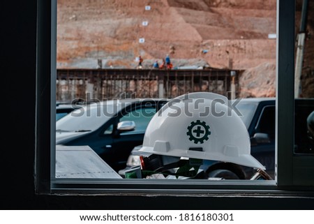 Safety helmet with the first aid symbol on the window frame against the background of the construction site.
