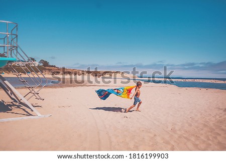 Boy running at the beach by a lifeguard tower