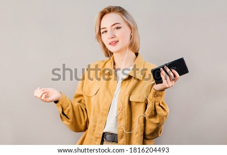 Close-up portrait of beautiful attractive European young woman, relaxing, listening to her favourite songs via white earphones, using music app.
