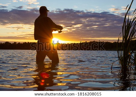 Silhouette of angler catching the fish durring sunset with lens flare defect.
 Royalty-Free Stock Photo #1816208015