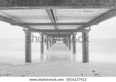 Massive concrete pier leading to horizon surrounded by Mediterranean sea. Long exposure shot made in Belek, Turkey. August 2020. Black and white picture
