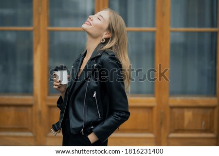 happy beautiful elegant modern woman blonde European appearance, in a black stylish leather jacket posing for the camera model, Sunny summer warm day