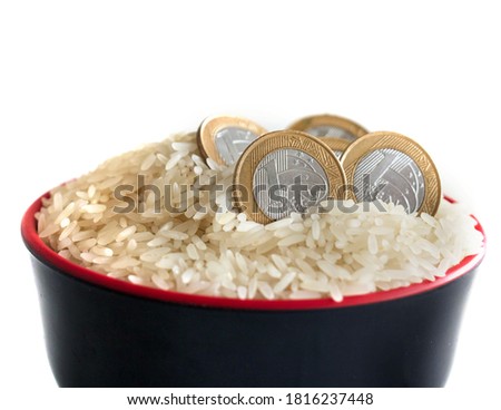 Expensive rice in Brazil due economic pandemic crisis. Brazilian coins inside raw rice grains bowl.  Concept of rising rice prices in the Brazilian basic basket, return of inflation. White background.