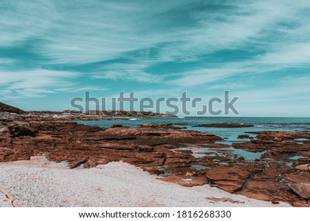 Astonishing views from rocky cliffs with a deep blue ocean on the background and plenty of white clouds spread in the sky reflected on natural pools of water