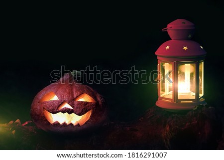 Head jack pumpkin and lantern on ground in scary and spooky deep night. Halloween pumpkin jack-o-lantern with burning candles and lantern with copy space.