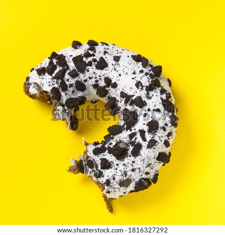 chocolate donut with white glaze isolated on yellow background, close up.
