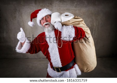 Smiling Santa Claus holding a sack full of toilet paper and giving the thumbs up sign during a pandemic
