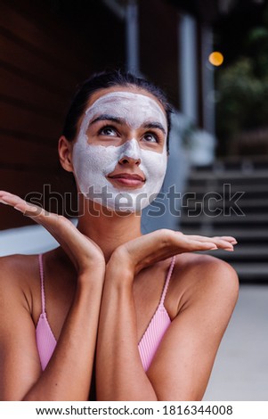 Outdoor portrait of tanned skin calm pretty caucasian woman in bikini at spa with white peeling mask on face