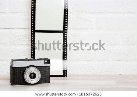 Old retro camera with  camera film agianst white brick wall. Space for text or image. 