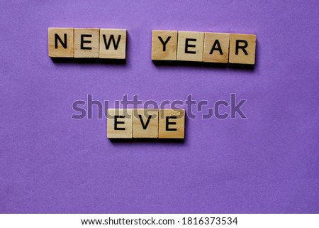 Words New Year Eve. Wooden blocks with inscription on purple background. The bulletin board. Concept of holiday-Christmas and New year. View from above. Copy space for Text. Christmas and New Year.