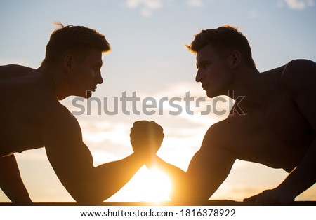 Rivalry, vs, challenge, hand wrestling. Sunset, sunrise. Men measuring forces, arms. Two men arm wrestling. Silhouette of hands that compete in strength. Rivalry, closeup of male arm wrestling.