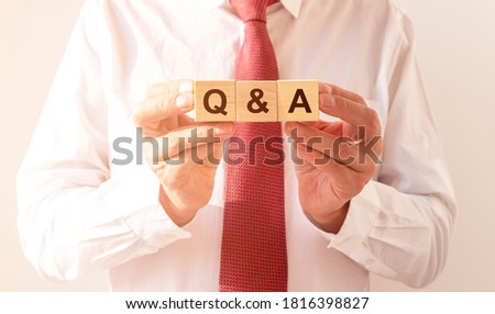 Q and A - Questions and Answers text sign on wooden cube blocks of white t-shirt with red tie, faq