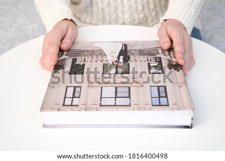 women's hands hold a wedding photo book on the table. convenient, beautiful and long-lasting storage of photos from photo sessions.