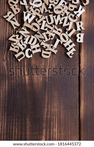 Letters of the English alphabet on a dark wooden background. The concept of education, word games, needlework. Space for text