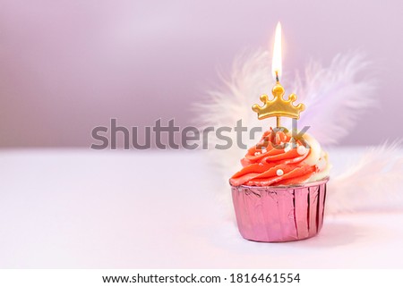 Composition with festive cupcakes with pink cream and a candle on a pink background. Copy space