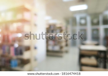 Blurred of the interior of the public library with wooden tables, chairs and books in bookshelves. Education and book's day background concept.