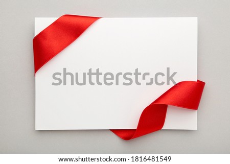 Close up of a note card with ribbon bow on grey background. Top view.