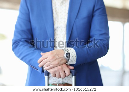 Businessman hold handle of suitcase. Man in blue jacket and shirt stand with his hand folded one by one.