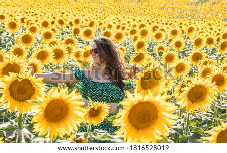 young woman dressed in green and with red sunglasses pictured among sunflowers in Guadalajara, Spain
