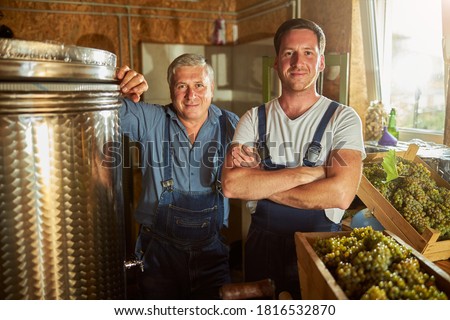 Joyful father and son standing at the winery while looking at the camera