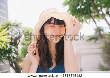 Portrait of young asian woman traveler wearing blue dress and hat outdoors in city.