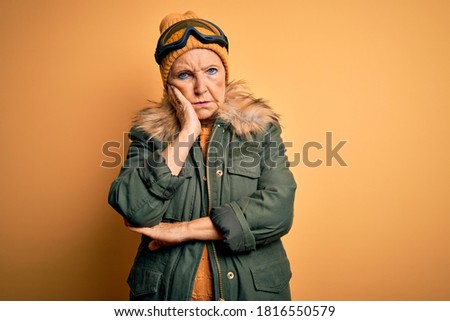 Senior beautiful grey-haired skier woman wearing snow sportswear and ski goggles thinking looking tired and bored with depression problems with crossed arms.